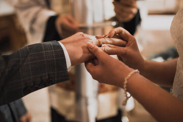 The bride and groom exchange rings. A man puts a wedding ring on a woman's hand. The girl put ring on man.
