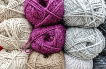 Colorful woolen balls of yarn. Background of colored yarn balls. Needlework. Knitting. Hobbies and leisure. Balls of yarn in shades of neutral, lilac, grey, khaki colors.