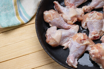 fresh chicken wings at frying pan on a wooden desk. cooking hen wing