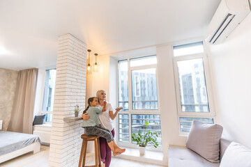 Mother in sportswear with daughter standing near the air conditioning