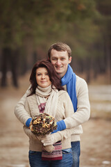 couple on winter walk in snow. Valentine's Day  for couple in rustic style. Happy couple in love warming themselves with tea under a blanket in the arms of nature. Casual outfit with Blue accessories