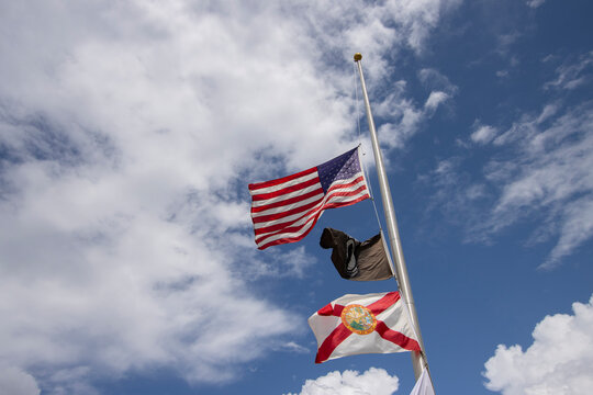 Flags flying at half mast including the IA POW flag and the Florida State flag
