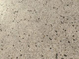 Small stones and rocks embedded in a flat, cement surface, creating abstract texture background