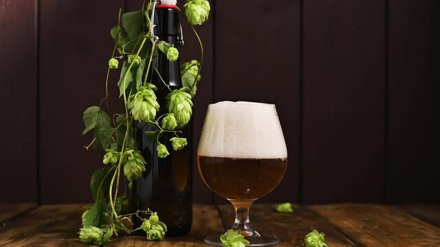Beer. Cold Craft light Beer in a glass with water drops. Pint of Beer close up on a wooden background. Beer is pouring from the bottle. Border design. High quality 4k footage