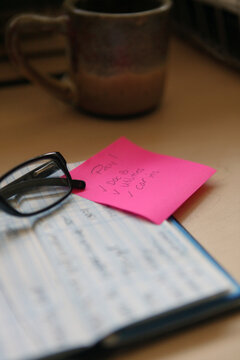 Check book and note sitting on a desk with a coffee cup