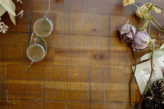 Vintage wire glasses on wooden table top with dried roses as frame