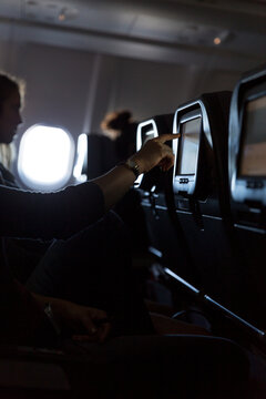 Person's hand touching in-flight entertainment screen