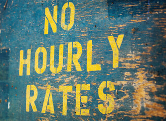 An old wooden sign stating No Hourly Rates