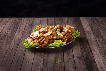 Tasty portion of fried chicken with rustic onions, bacon, olives and lettuce. Fried Chicken with Passarinho. Typical Brazilian food. Gourmet photography with centralized elements. Spaces for texts.