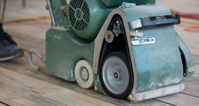 Carpenter sanding a wooden floor with sander machine
