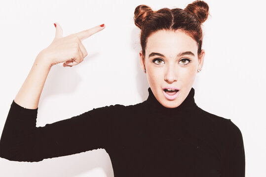 Beautiful girl with buns pointing at her hairstyle.