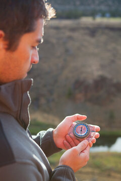 Man holding compass outside at sunrise