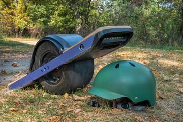 One-wheeled electric skateboard with a helmet on a forest trail, early fall scenery in Nebraska