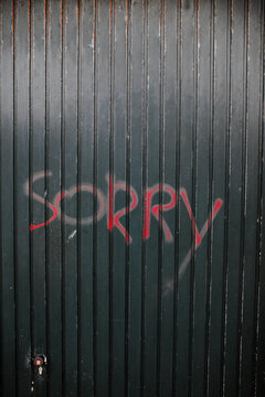 The word 'sorry' painted on an old garagedoor