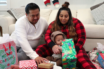 Interracial Filipino and Mexican Parents Sitting At Home Opening Christmas Presents With Their Baby Boy In A Onesie