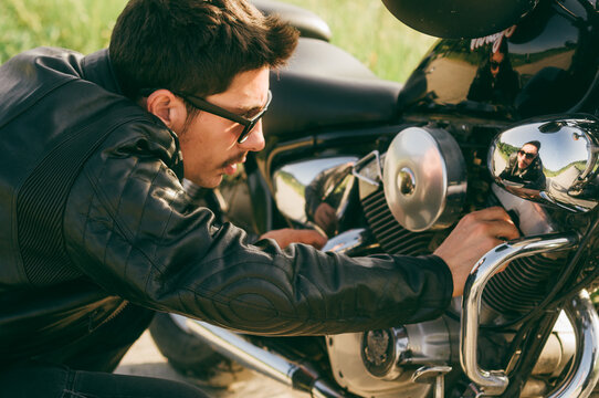 Young man checking engine on his bike