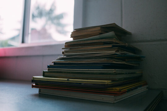 Pile of old books, and magazines beside a window