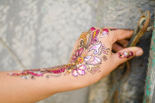 A floral deigned haenna painted hand unlocking a rusty chain .