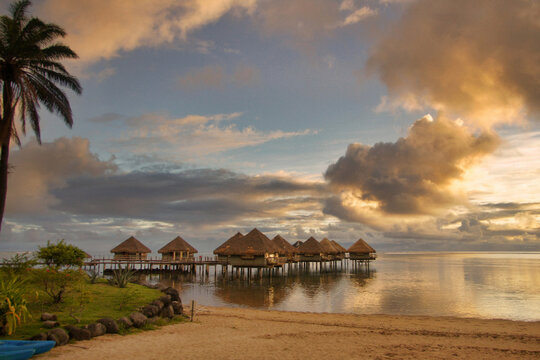 Paradise beach on Tahiti, with luxury bungalows at sunset