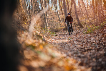 Naklejka na ściany i meble Young man riding mountain bike through forest