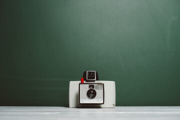 White polaroid camera in front of green background