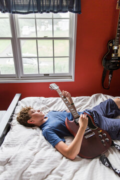 Teenage Boy in Room Practicing Guitar