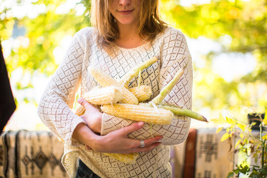 Young blonde woman carries copious amounts of corn