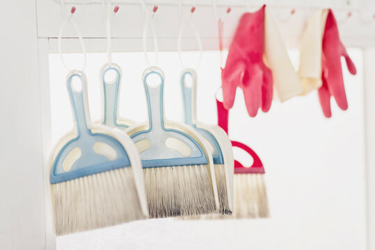Brooms and plastic gloves hanging in front of the glass window