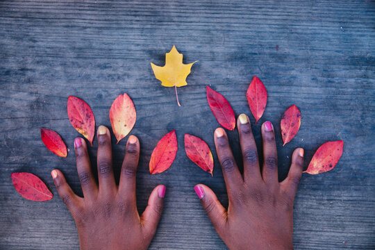 African American girl's hands with decorative fall leaves pattern