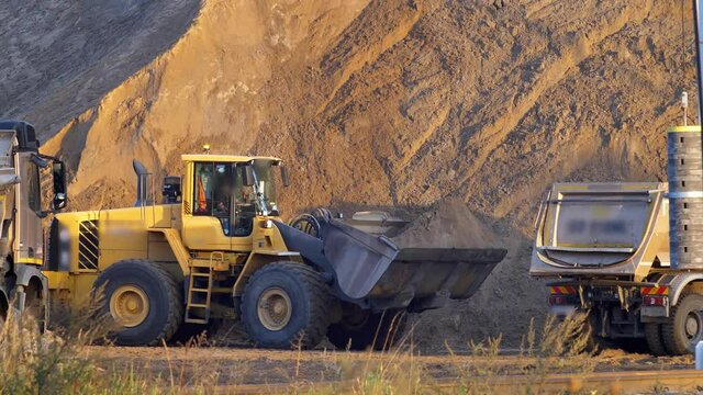 Front Loader Loading Sand on Dumper Trucks on Construction Site