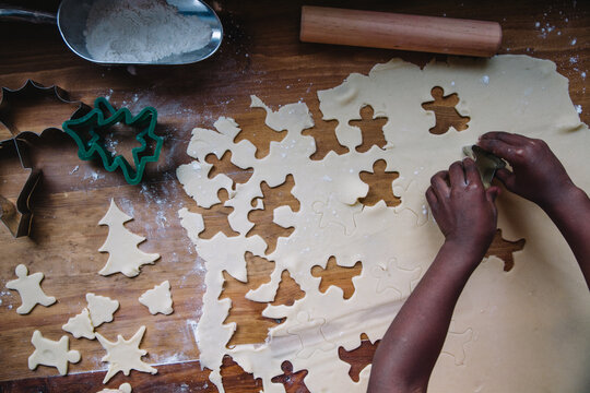 African American girl's hands cutting ginger bread man shapes on a cookie dough