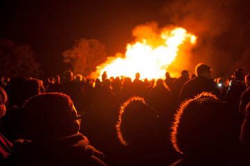 people in silhouette watching a public bonfire