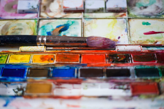 Paint brush on top of a palette of paints