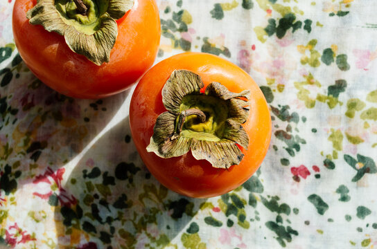 Kaki fruits: two persimmon on a table, shoot from above