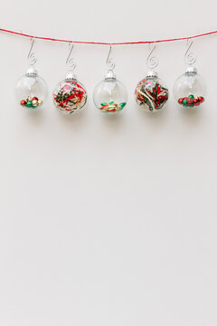 Five glass Christmas ornaments hanging from red string