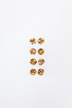 Hand cut blister pack imitation with unordered golden pills and capsules under it.