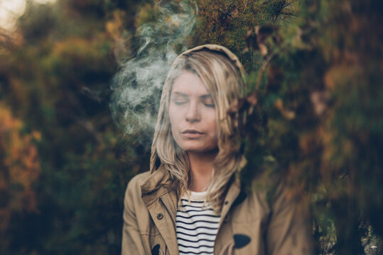 Portrait of a woman smoking in the forest, in autumn.