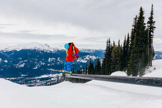 Skier sliding on a rail in a snowpark of ski resort