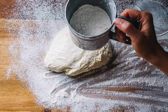 Woman's hand dusting flour on a bread dough
