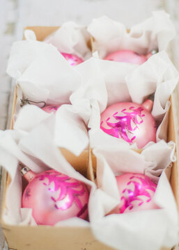 Pink antique glass Christmas ornaments in a brown box on white