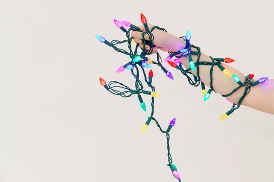 Arm tangled in Christmas lights on white