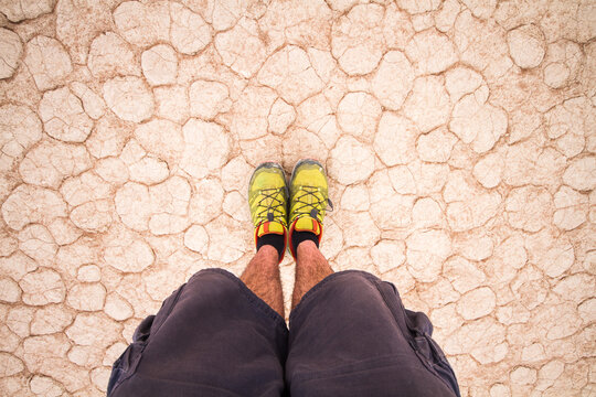 Feet POV view of adventure traveler on dry parched ground on the desert