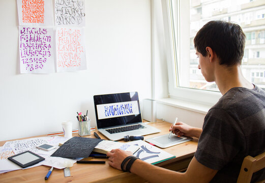 Freelance graphic designer working on the computer tablet by the window