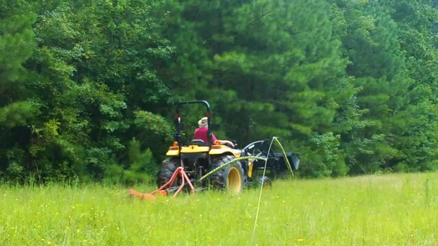 A man on a tractor mowing field with brush hog