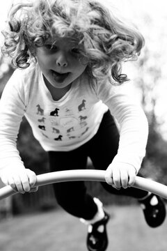 Black and white image of a girl bouncing on a trampoline