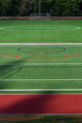 Newly installed artificial turf sports field on a sunny day, soccer goals
