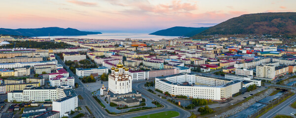 Beautiful panorama of the city of Magadan. Beautiful morning cityscape. Aerial view of the cathedral, streets, buildings, mountains and sea bay. Magadan, Magadan region, Russian Far East, Siberia.