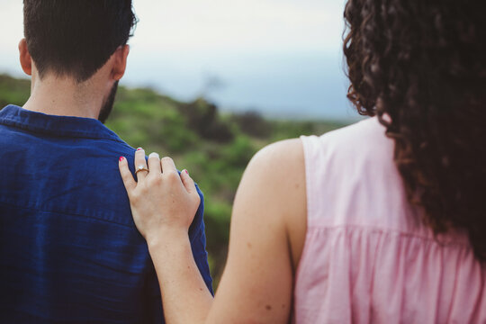 Young couple walking together in nature - woman has hand with engagement ring on man's shoulder