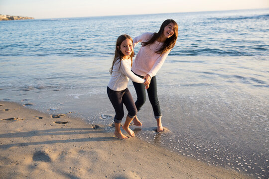 Beautiful sisters playing on the shore at the beach