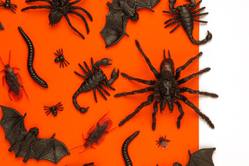 Black Halloween creepy crawly bugs and spiders on orange background with blank white space for text...